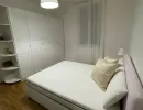 Camera da letto moderna: un comodo letto matrimoniale con testiera rosa, ampio armadio a muro bianco e pavimento in parquet. Catina Basi