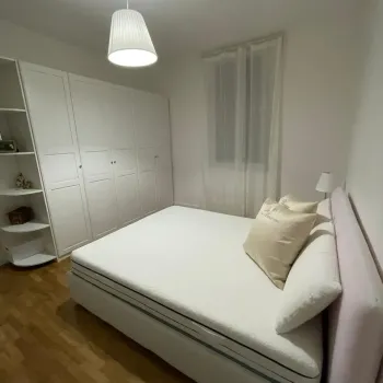 Camera da letto moderna: un comodo letto matrimoniale con testiera rosa, ampio armadio a muro bianco e pavimento in parquet. Catina Basi