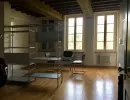 Luminoso studio o ufficio open space con eleganti pavimenti in legno e travi a vista. Arredato con sedie cantilever e una libreria industriale. Catina Basi