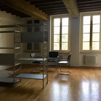 Luminoso studio o ufficio open space con eleganti pavimenti in legno e travi a vista. Arredato con sedie cantilever e una libreria industriale. Catina Basi