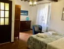 Accogliente camera da letto in stile rustico con pavimento in cotto e travi a vista. Arredata con letto matrimoniale, antico com&ograve; in legno e dettagli azzurri. Catina Basi