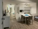 Camera da letto rustica con travi a vista e pavimento in cotto. Presenta un letto con testiera in legno, trapunta azzurra e un'originale scala a pioli decorativa. Catina Basi