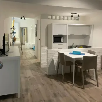 Camera da letto rustica con travi a vista e pavimento in cotto. Presenta un letto con testiera in legno, trapunta azzurra e un'originale scala a pioli decorativa. Catina Basi