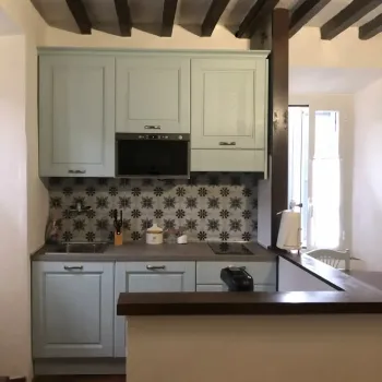 Cucina dal sapore tradizionale e accogliente: mobili azzurro pastello, comoda penisola, soffitto con travi in legno scuro e originali maioliche a parete. Catina Basi