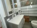 Bagno moderno caratterizzato da un elegante mobile lavabo sospeso bianco con ampi cassetti e specchiera contenitore coordinata. Catina Basi