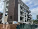 Edificio residenziale multipiano di moderna concezione caratterizzato da ampi balconi con parapetti in vetro scuro e rivestimenti verticali a effetto legno su una porzione della facciata